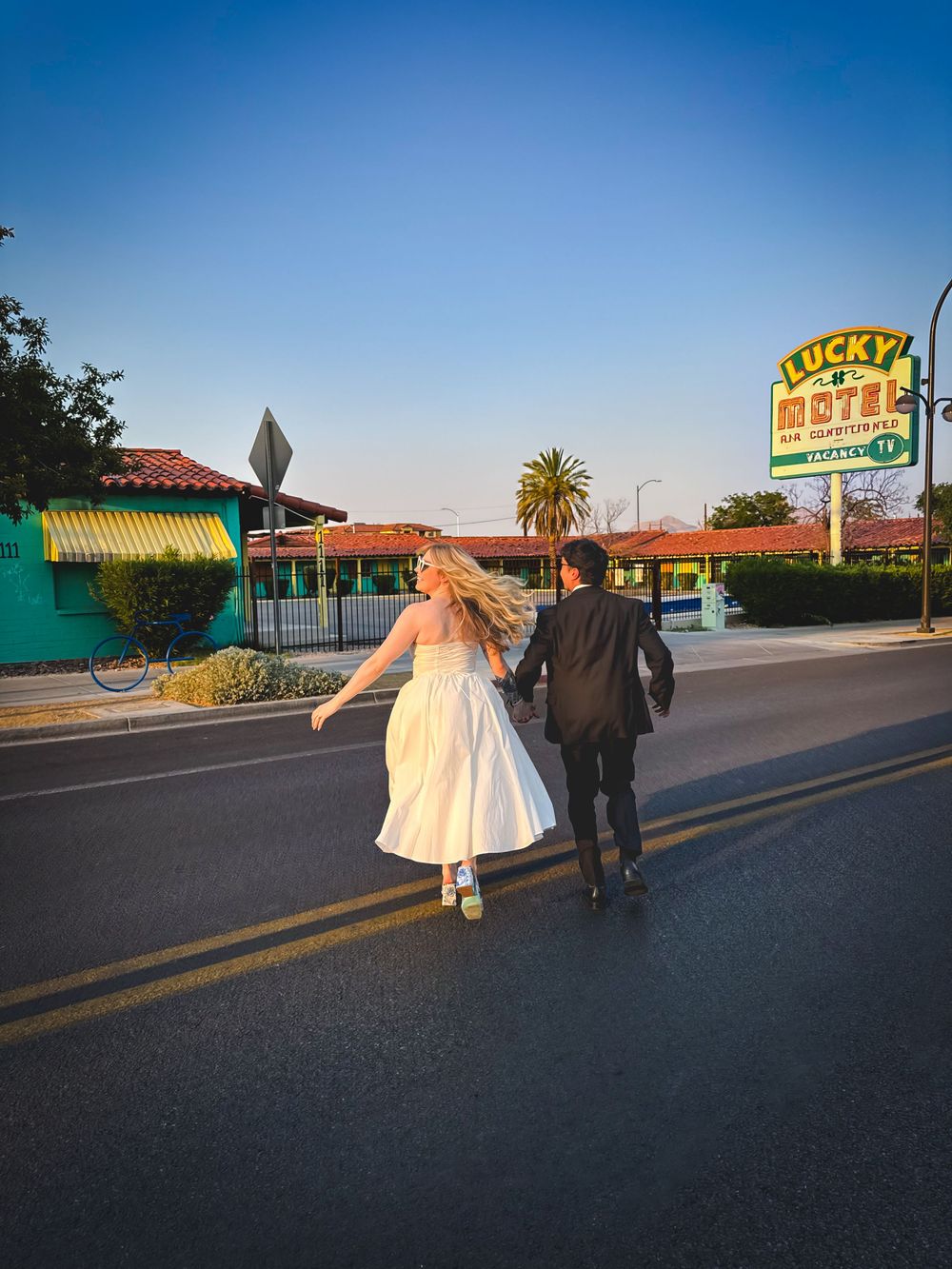 A couple walking away on a road with the famous Vaca Valley Motel sign visible in the background at sunset.
