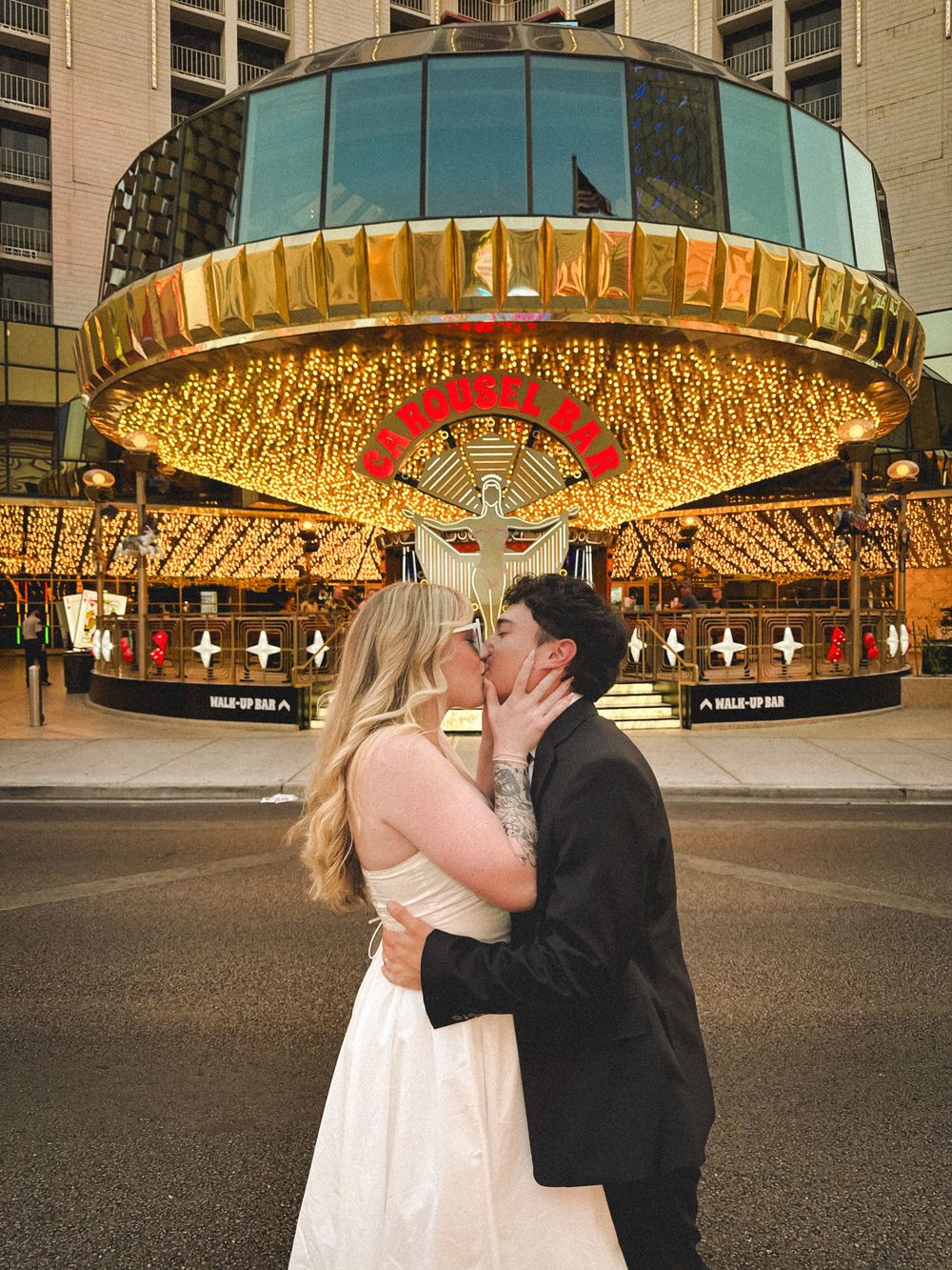 A carousel of four sequential photos showing a couple in wedding attire kissing under a golden-lit canopy.