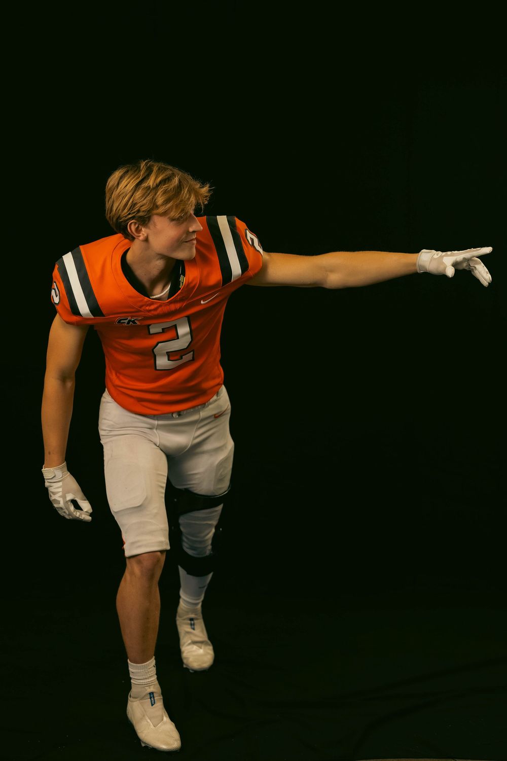 Football player in orange jersey demonstrates various dance or defensive stance poses against black background.