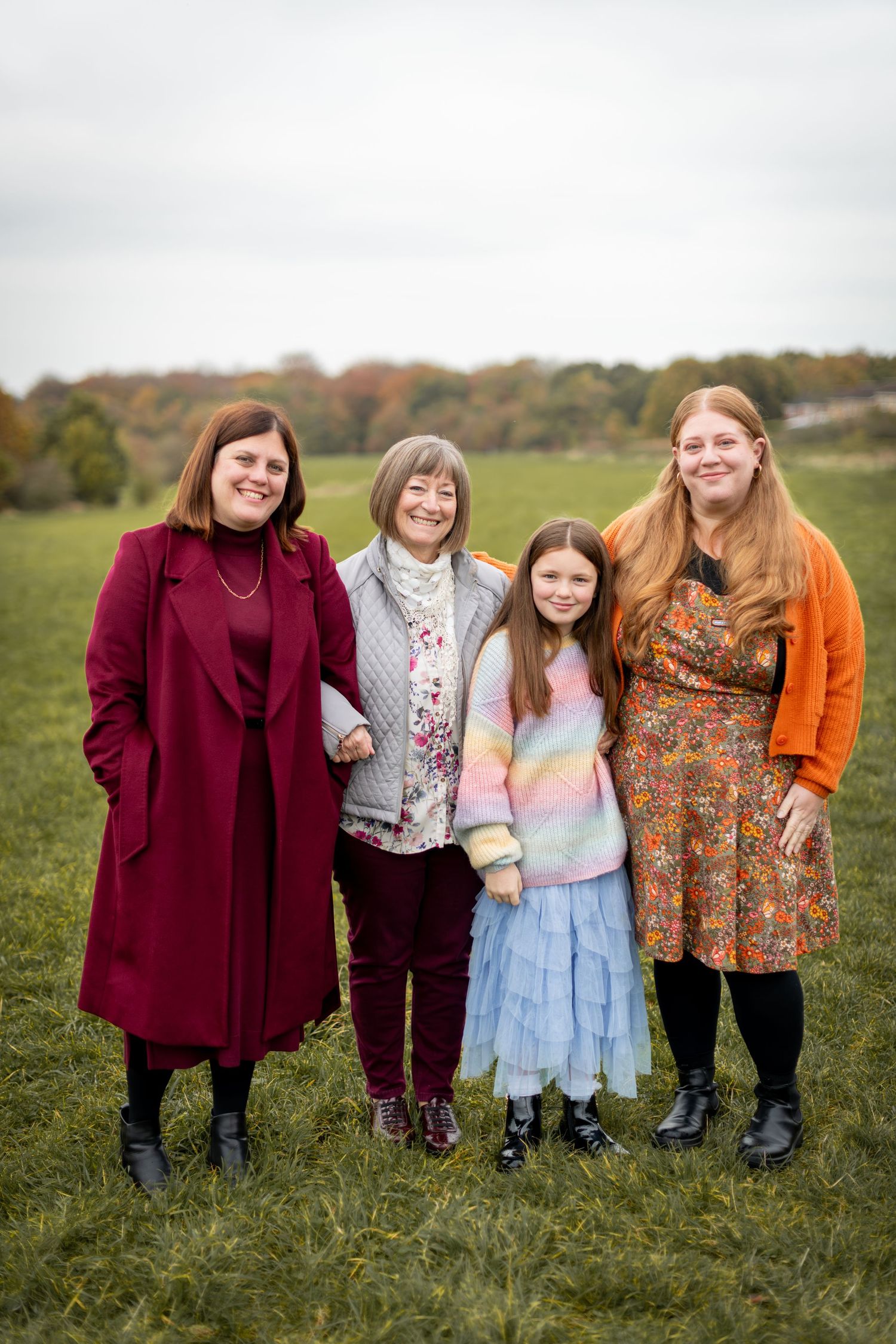 Family group portrait in autumn field wearing colorful outfits.