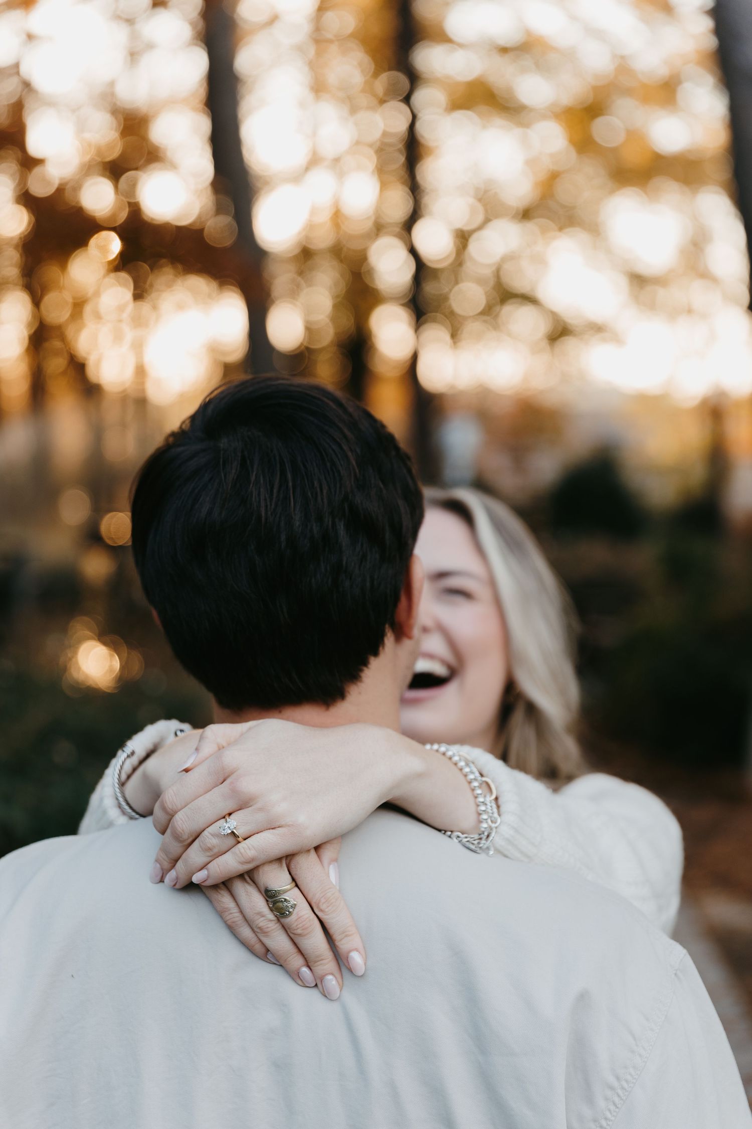 Couple embracing and laughing during sunset in autumn forest.