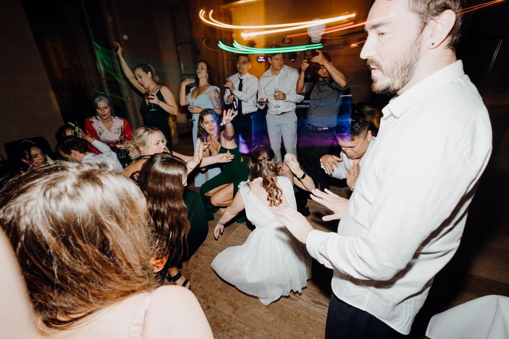A group of party guests dancing and celebrating enthusiastically, captured by Apertured Media Auckland Wedding Photographer.