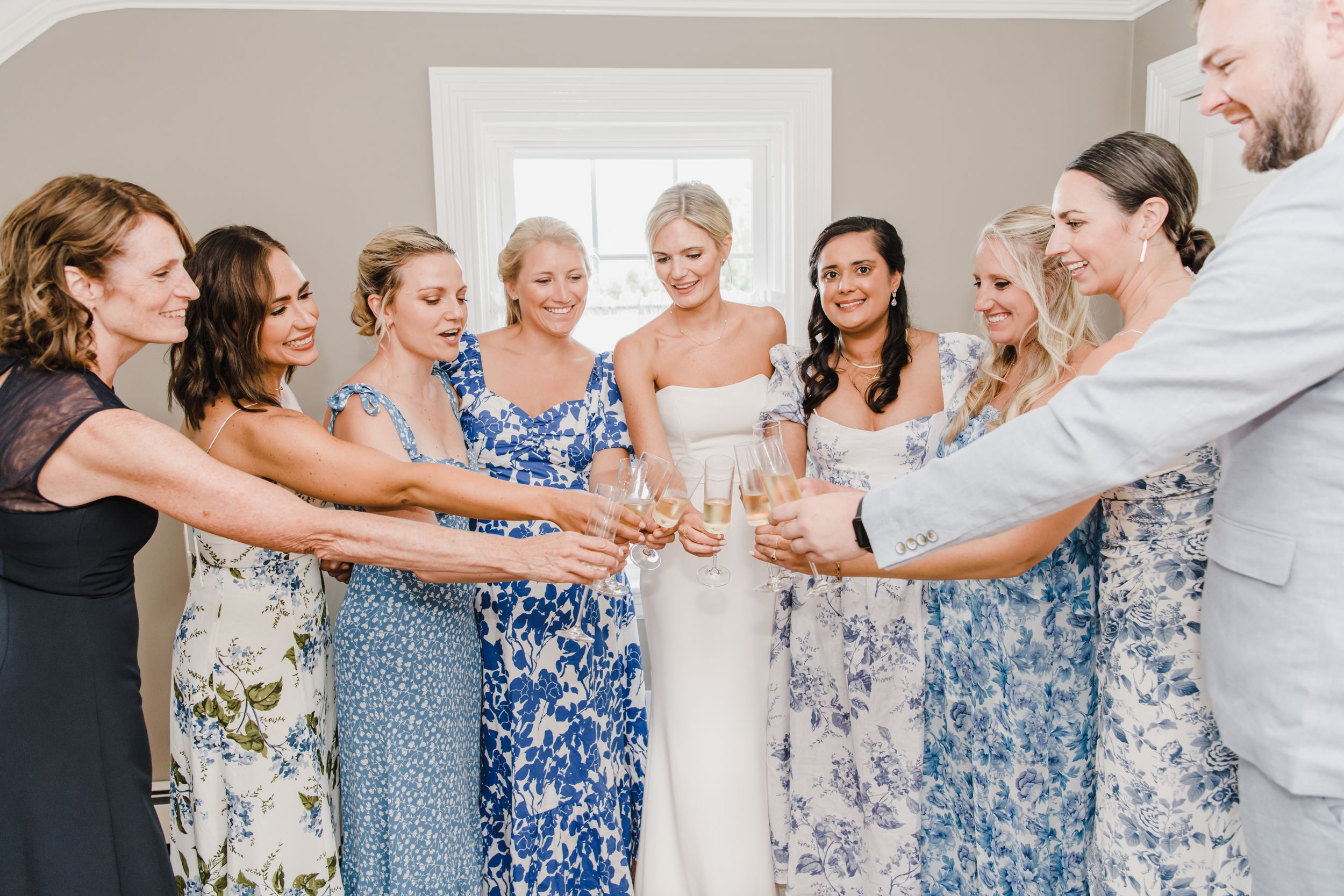 A group in floral blue dresses toast champagne glasses together in celebration at a special event.