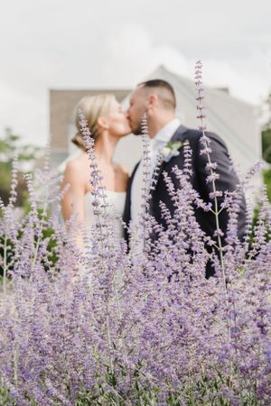 A romantic wedding moment captured through delicate purple lavender flowers blooming in the foreground.