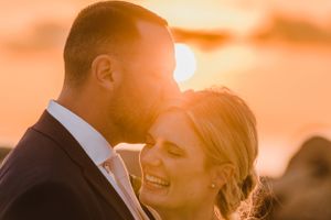 A joyful couple embraces at sunset with golden light creating a romantic silhouette and warm atmosphere.