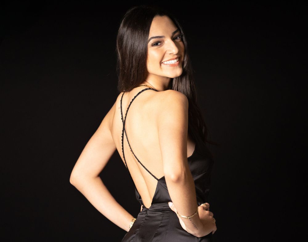 Elegant black backless evening dress photographed against dark background.