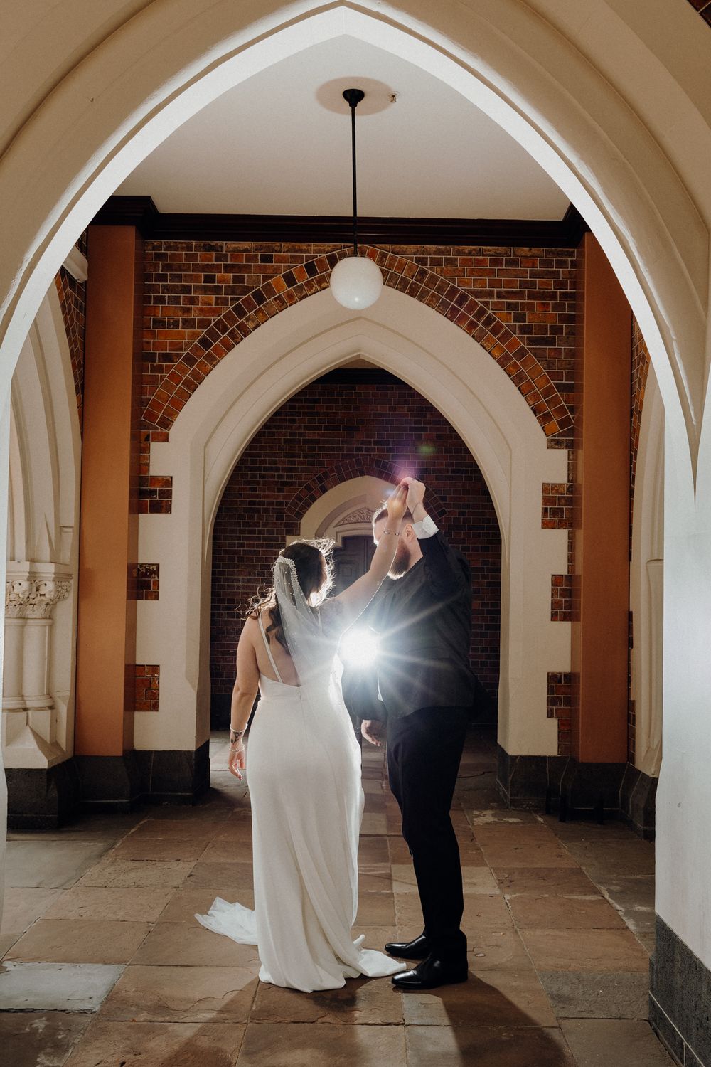 A couple dance together under a Gothic archwa, captured by Apertured Media Auckland Wedding Photographer.