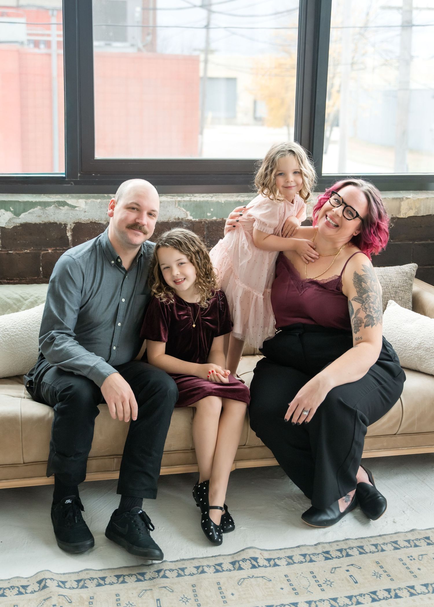 A family shares laughter while sitting together on a white couch in a casual indoor setting.