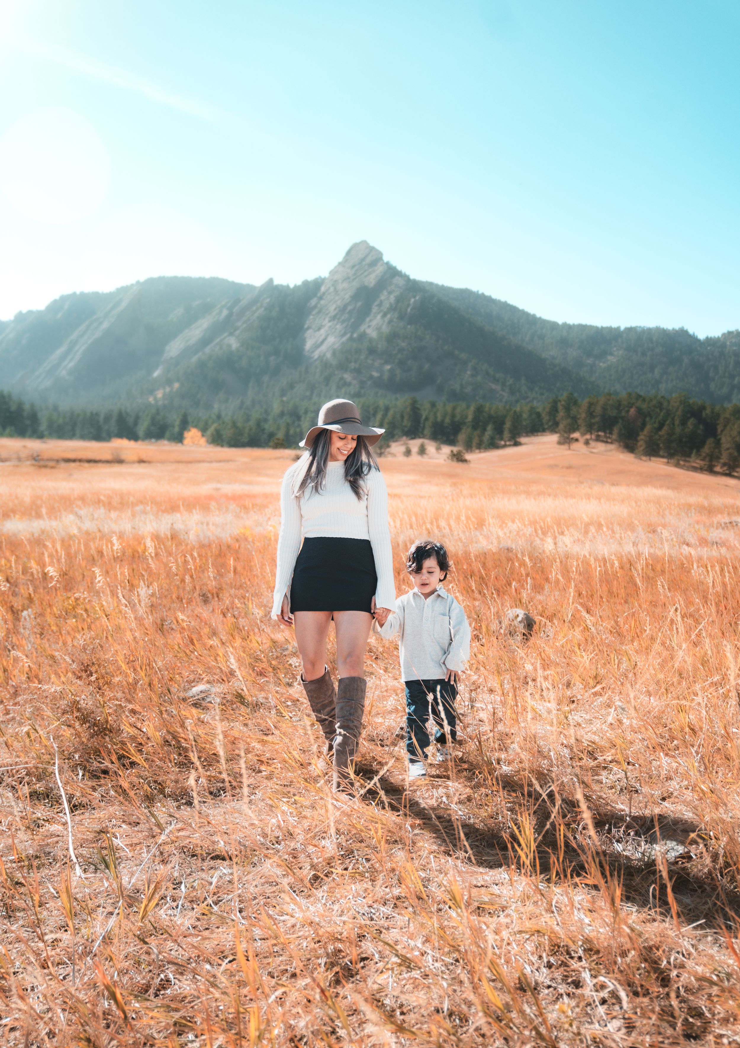 Three scenic landscape photos show people walking through a golden wheat field with mountains in the background.