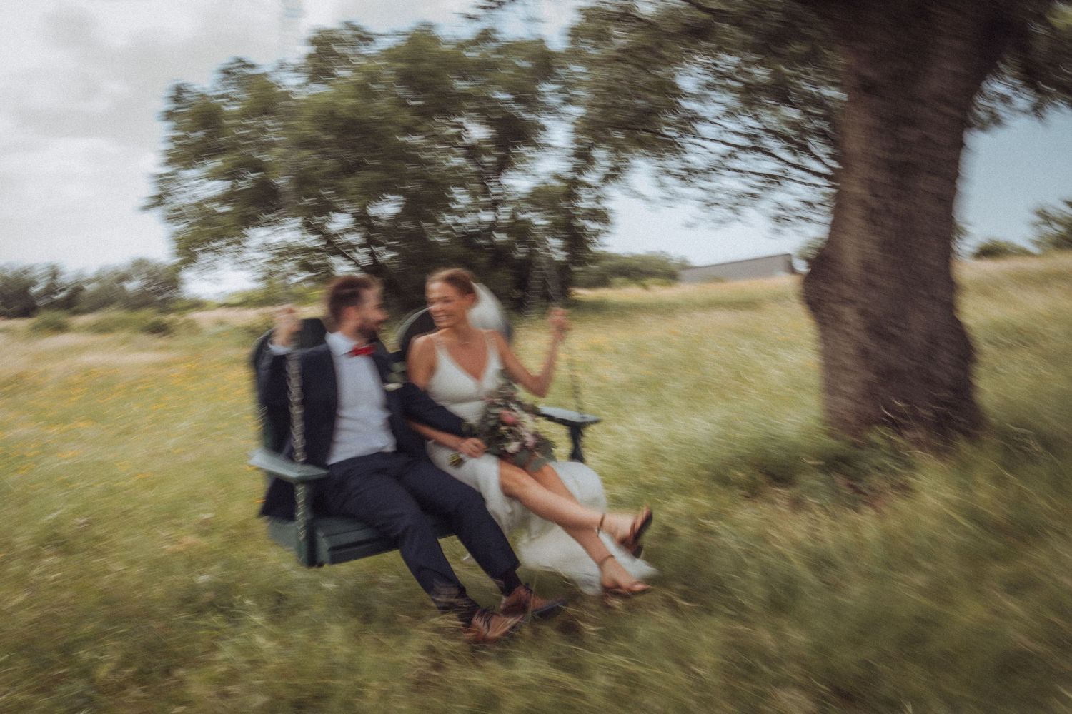 Couple poses in open field during golden hour sunset wedding photo session.