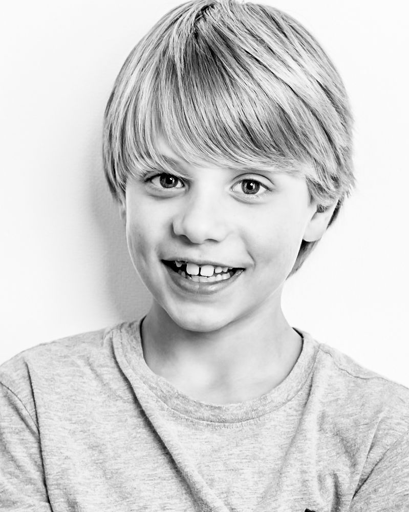 A series of four black and white portraits showing joyful expressions and genuine smiles against a plain background.