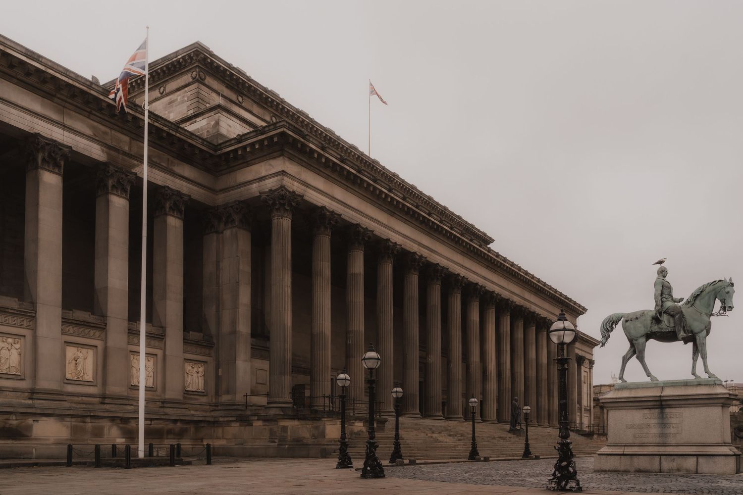 A panoramic view of St George's Hall in Liverpool with its neoclassical columns and equestrian statues along the facade.