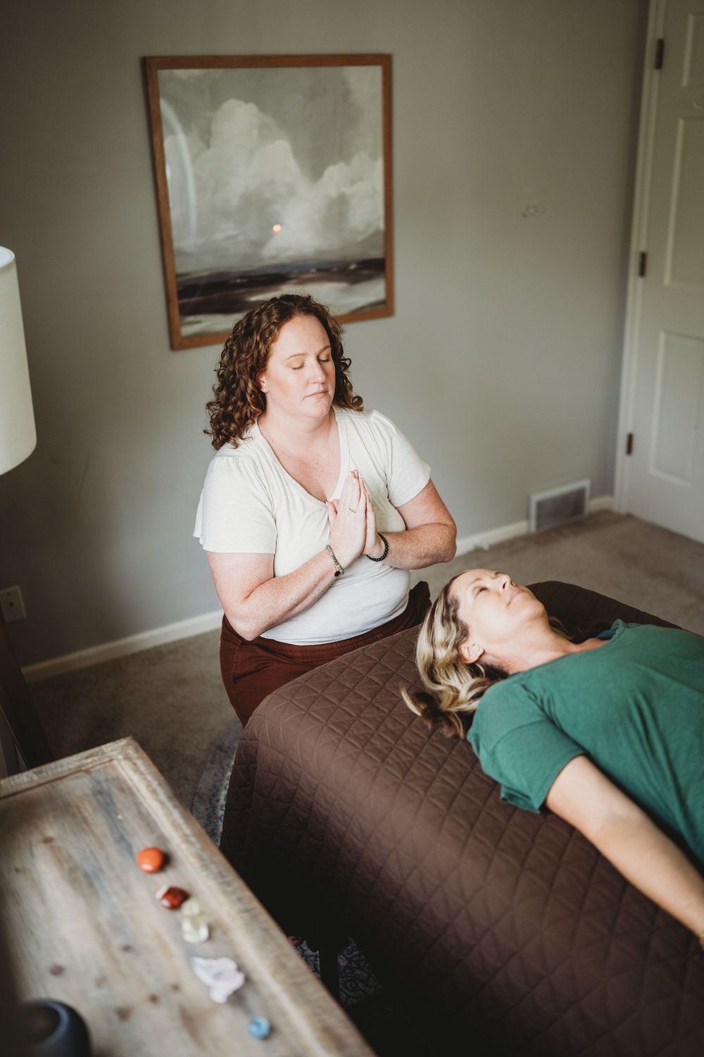 A massage therapist performs therapeutic treatment on a client lying on a brown massage table in a serene room.