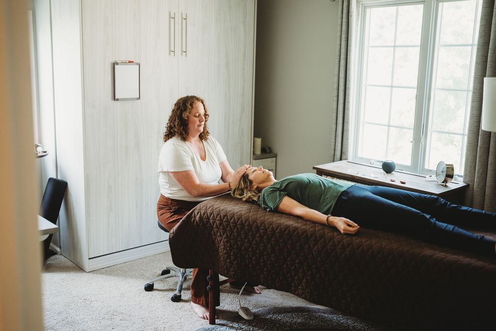 Woman in white sweater lounges comfortably on couch near bright windows in living room.