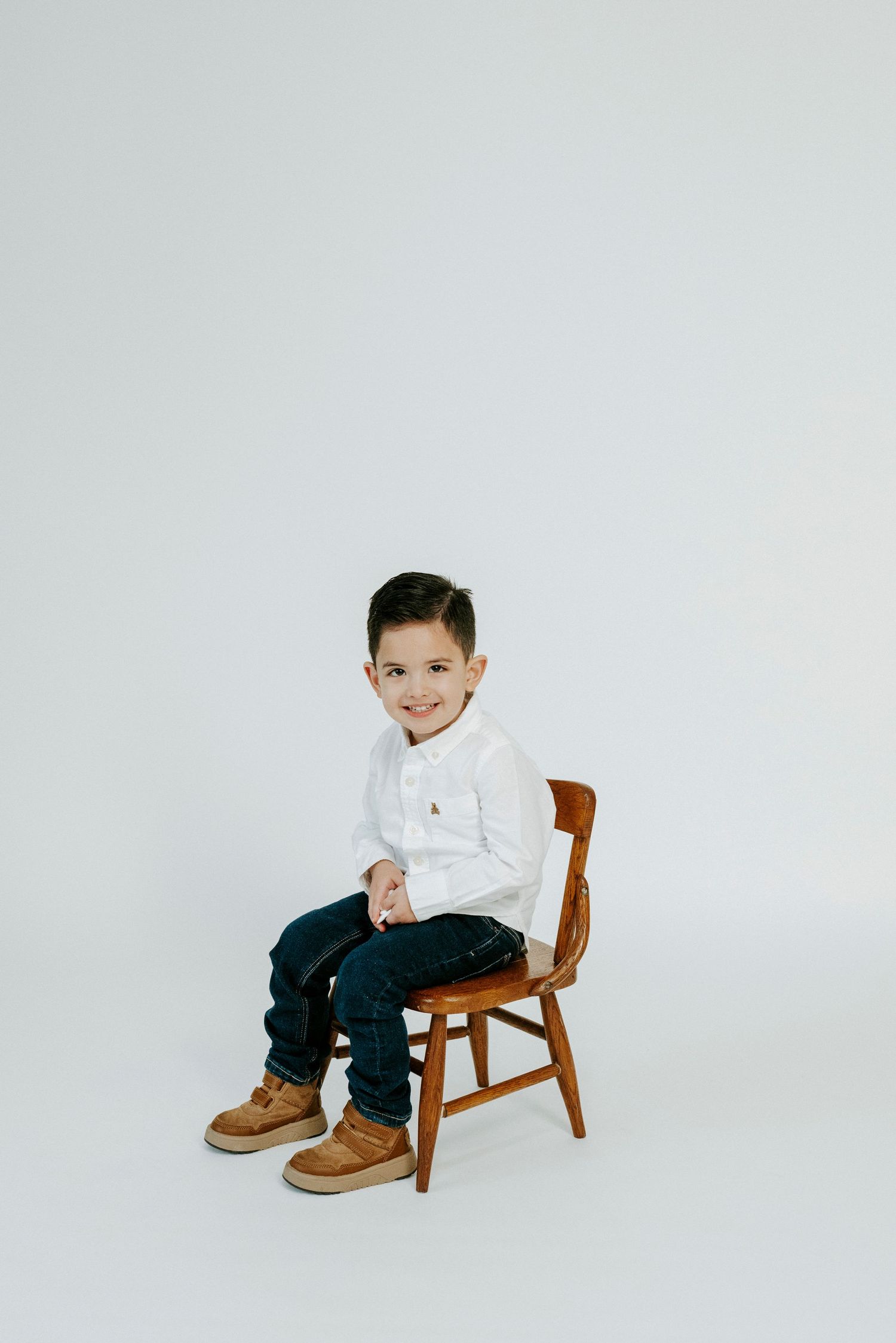 Three studio portraits of a child sitting on a wooden chair against a white background wearing casual clothing.