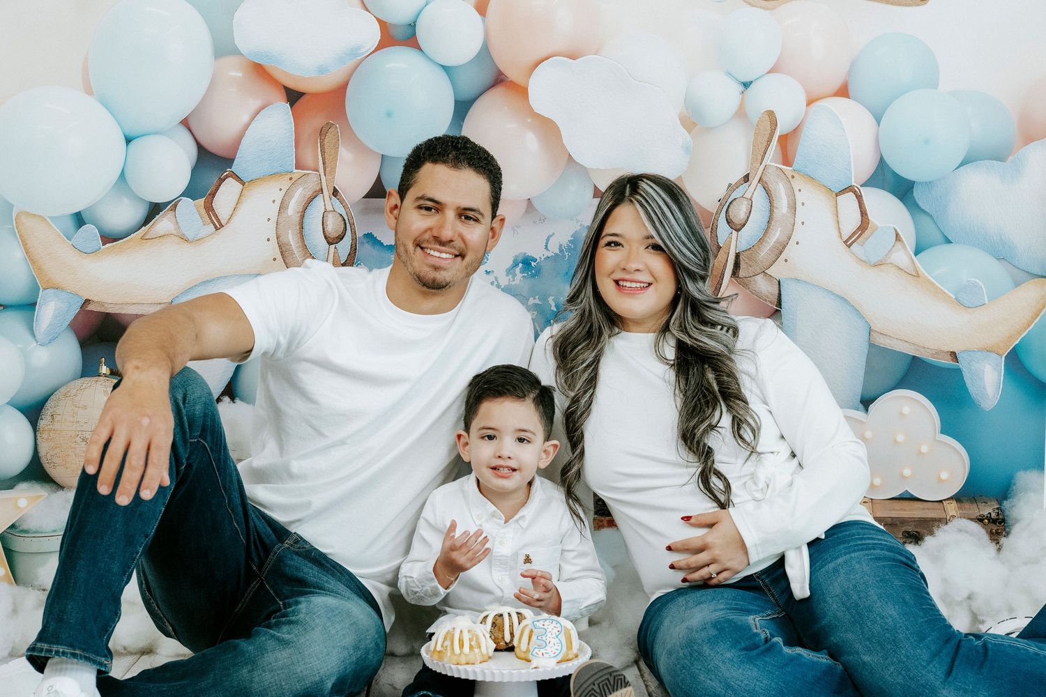A joyful group poses together on a couch with blue and white balloons creating a festive party atmosphere.
