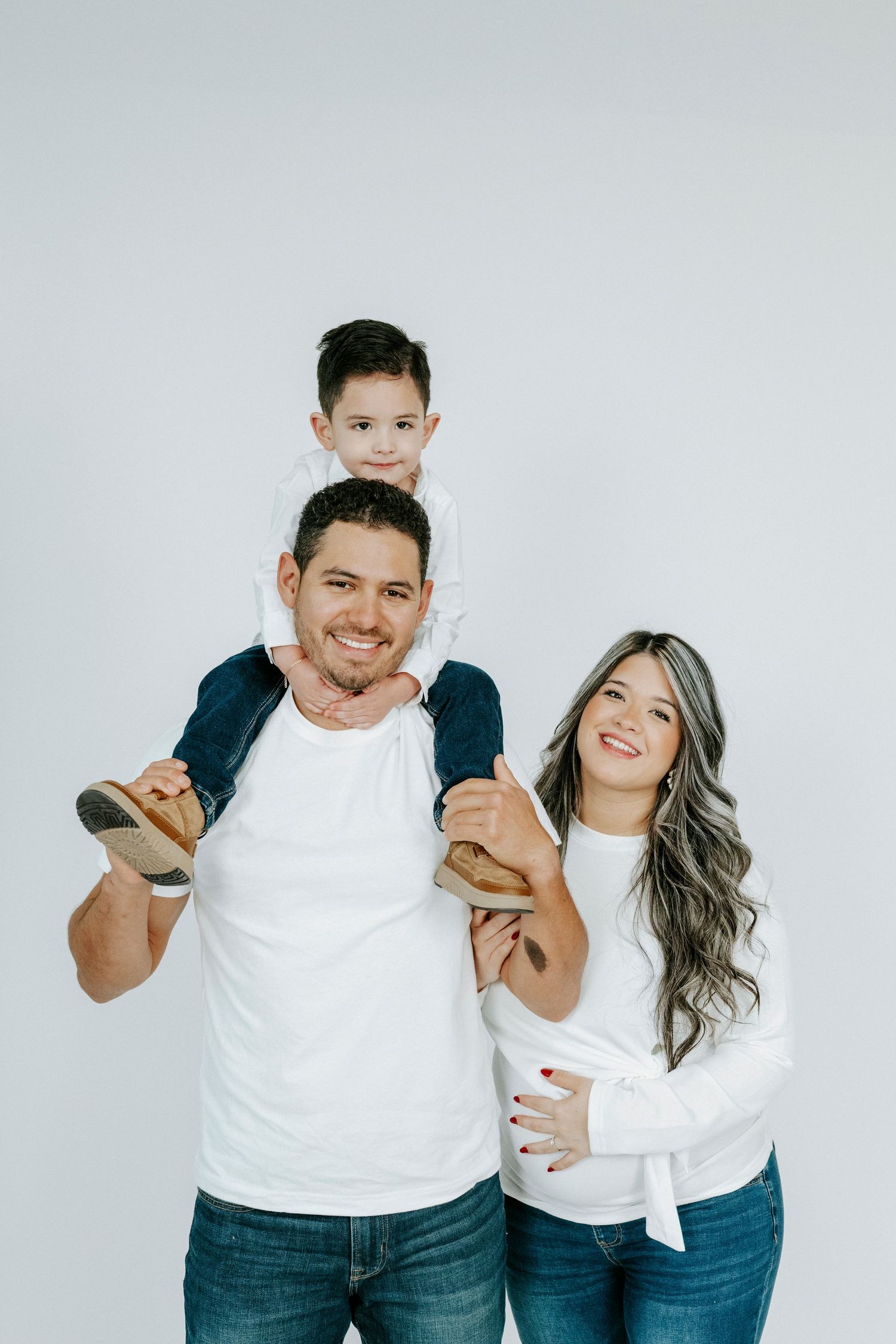 Family portrait series against a white background showing playful poses in coordinated white and blue outfits.
