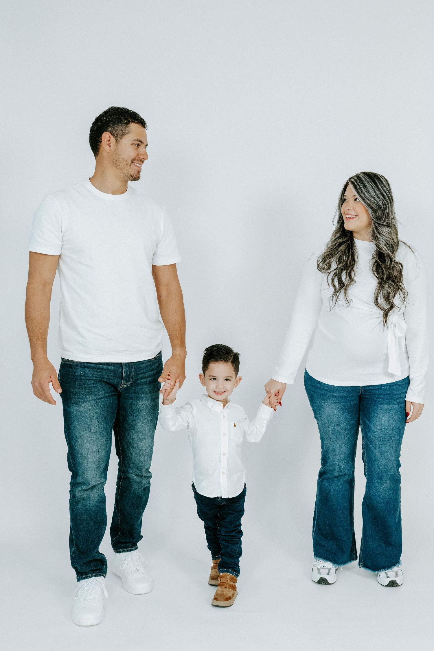Family members in matching casual outfits walk and interact together against a white backdrop.