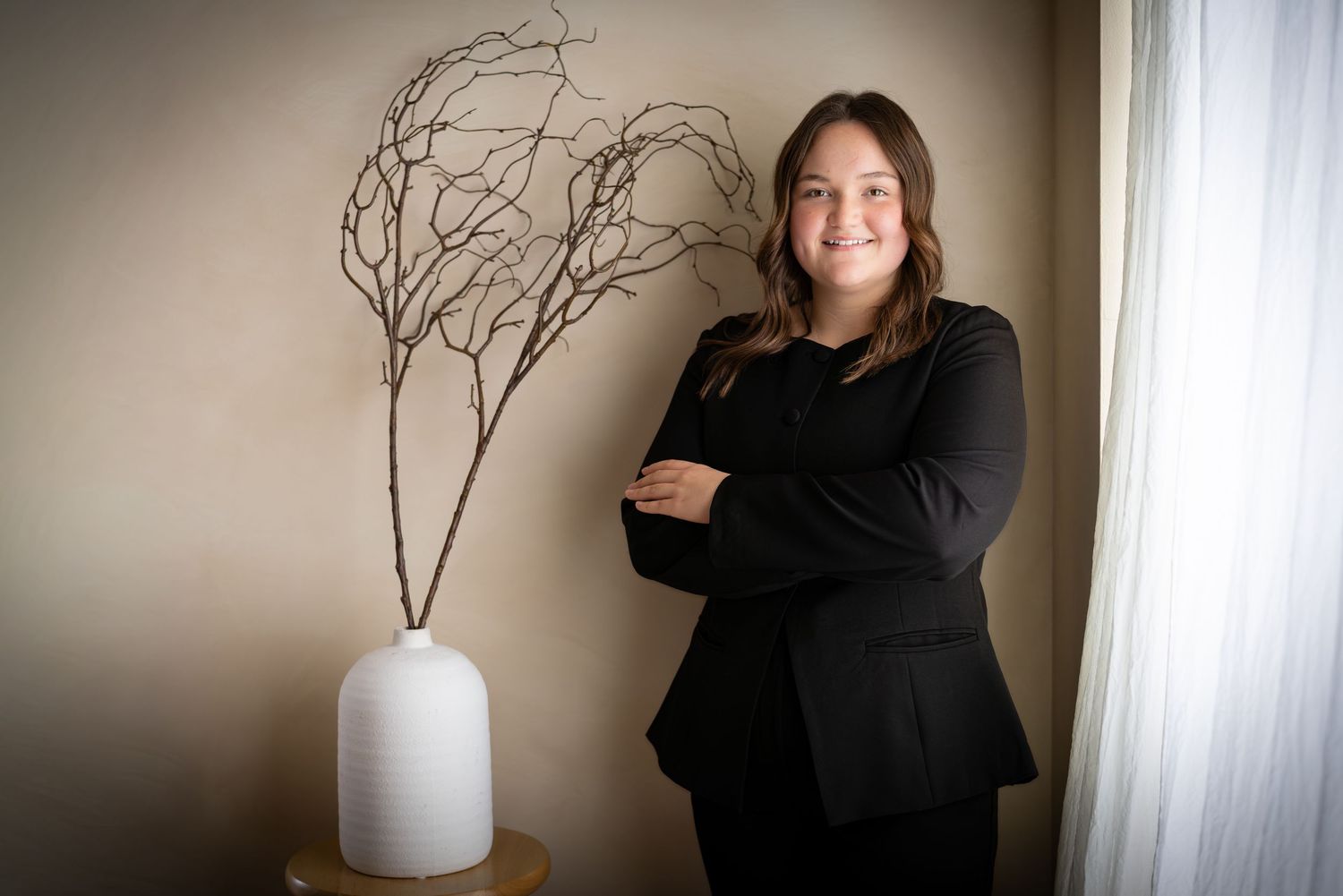A series of six minimalist photos showing a person in black against neutral backgrounds with branches and a white vase.