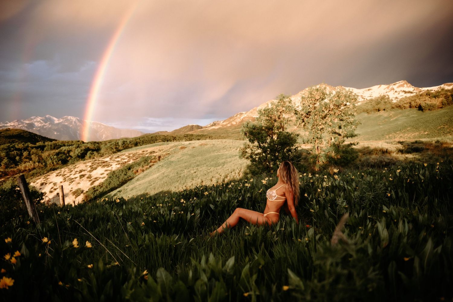 Outdoor Boudoir Photo of woman posing in Utah with red sky and wild flowers.