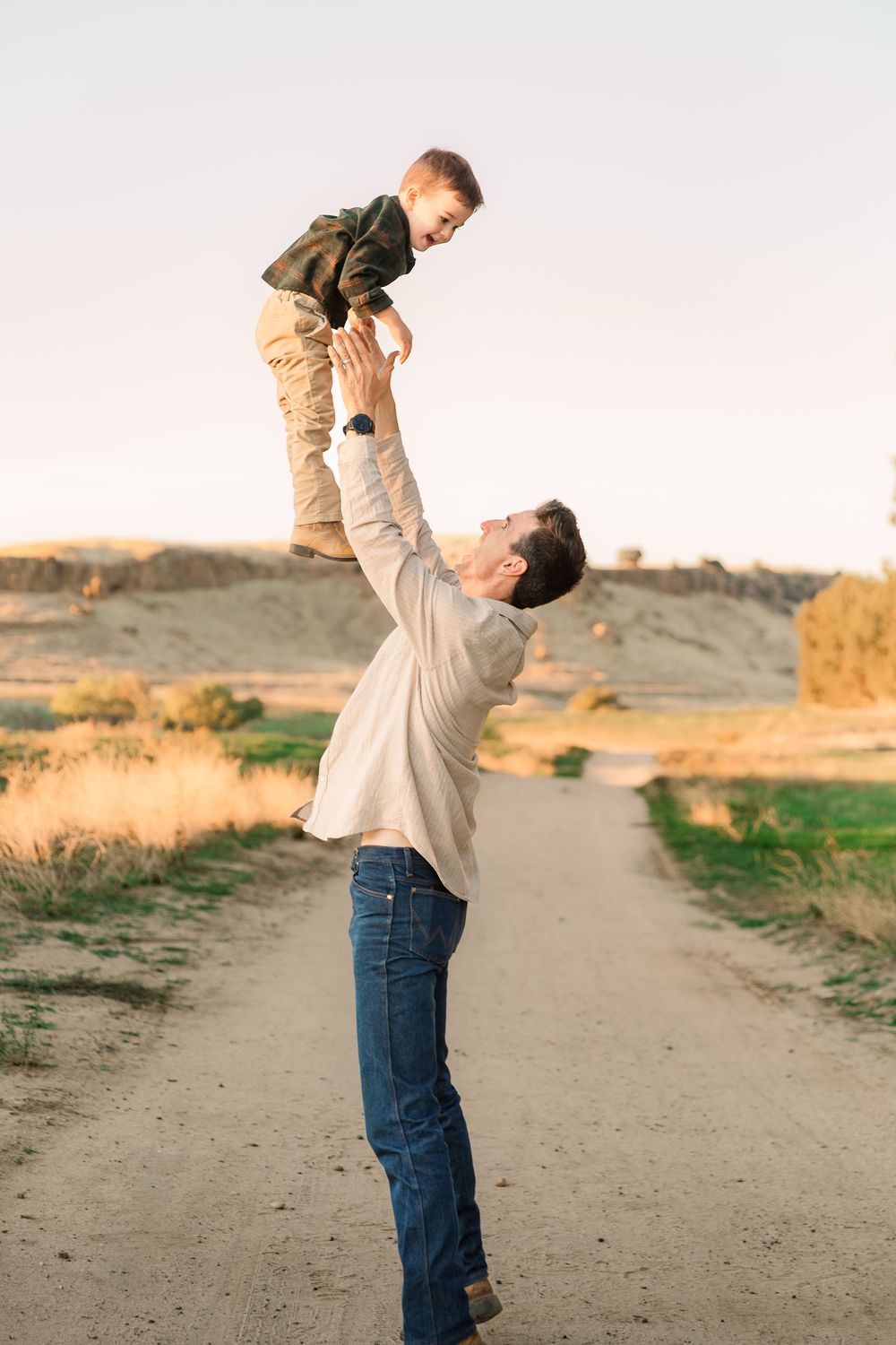 A playful moment captured on a dirt path with someone being lifted into the air.