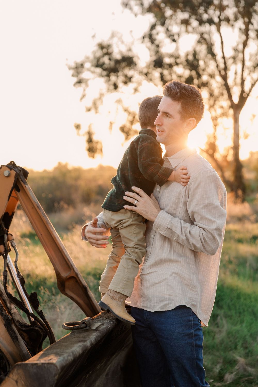 A child and adult sit together on wooden benches during golden hour in a natural setting.
