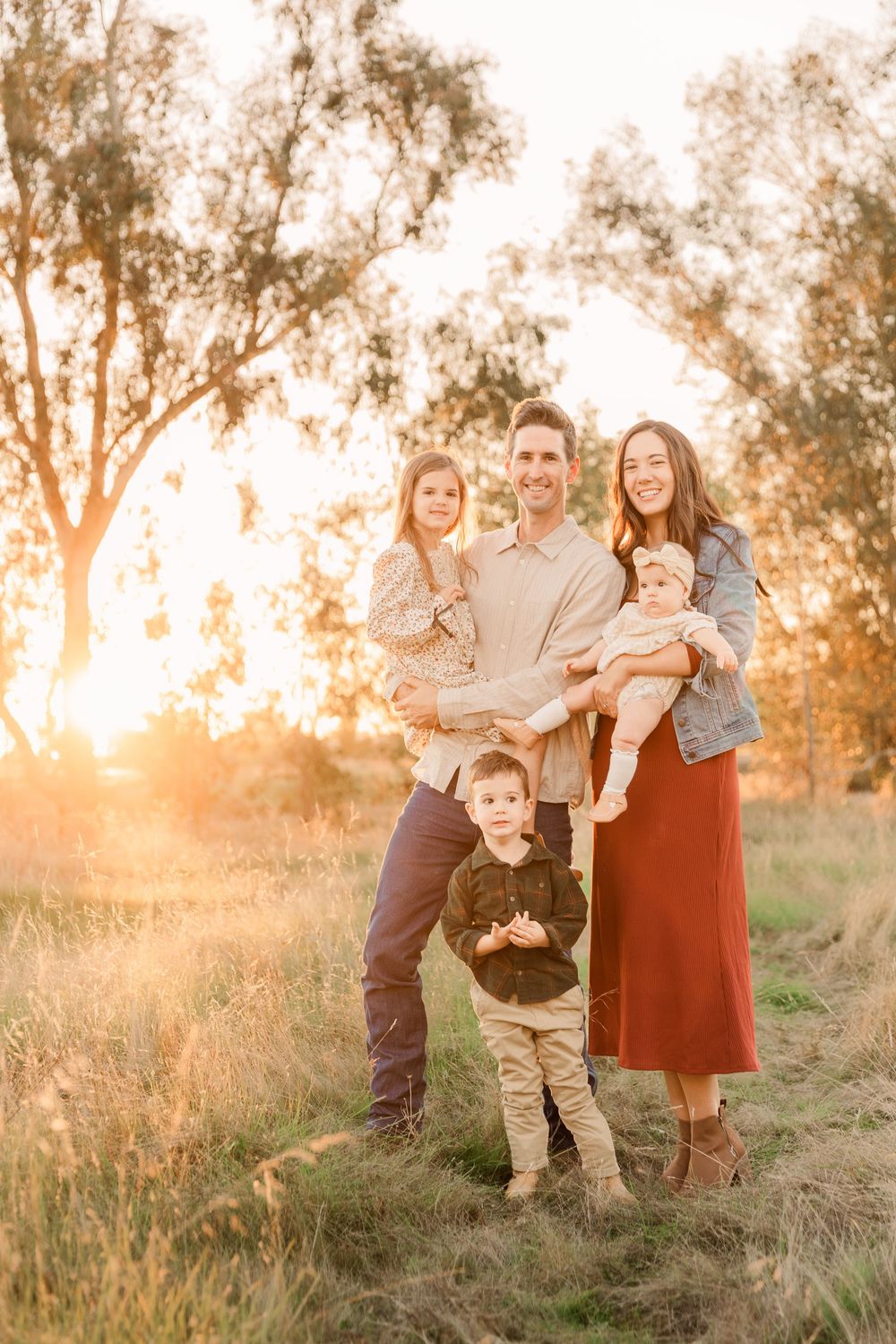 A family enjoys quality time together in a grassy field during sunset.