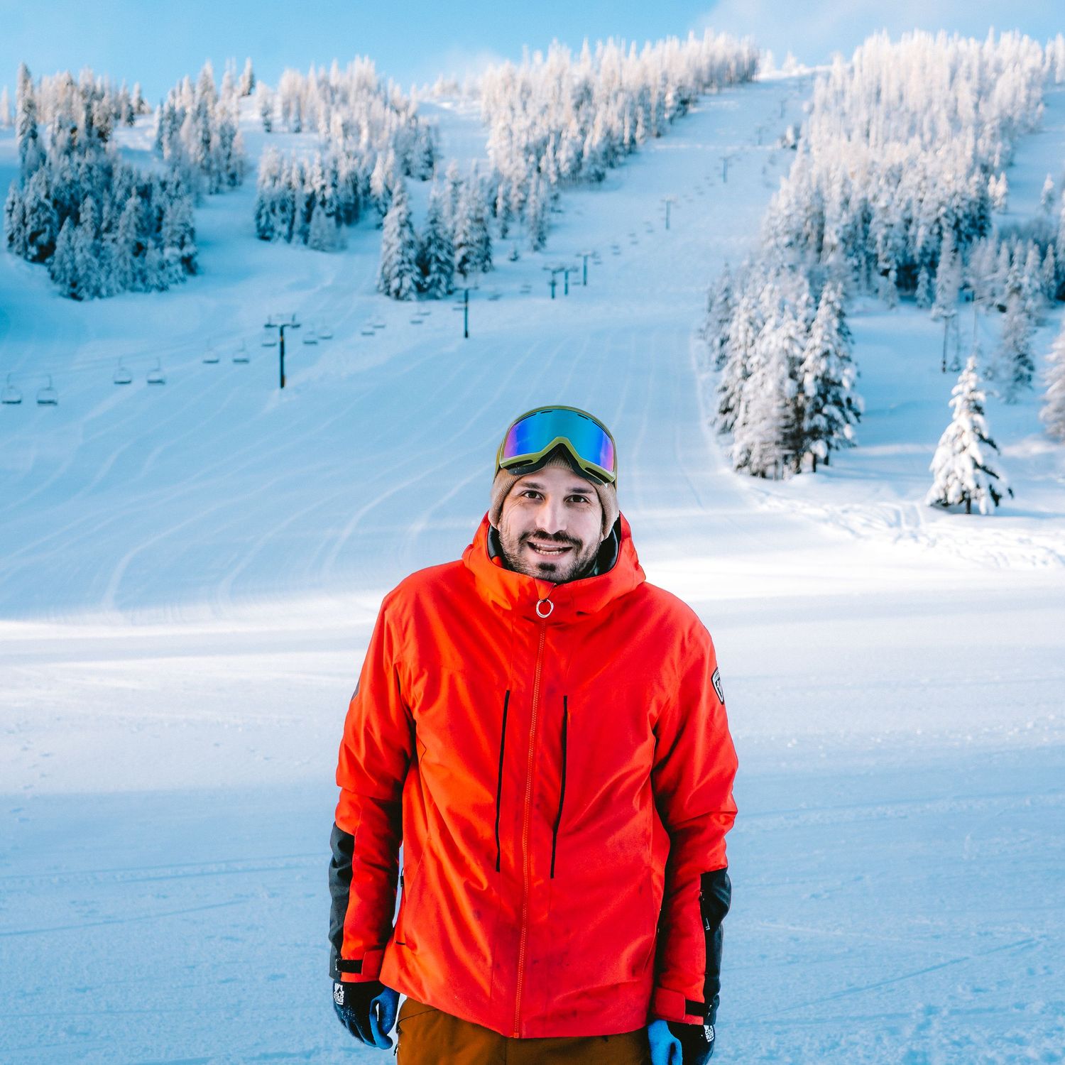 Snow-covered ski slopes with snow-laden evergreen trees in a winter mountain landscape.
