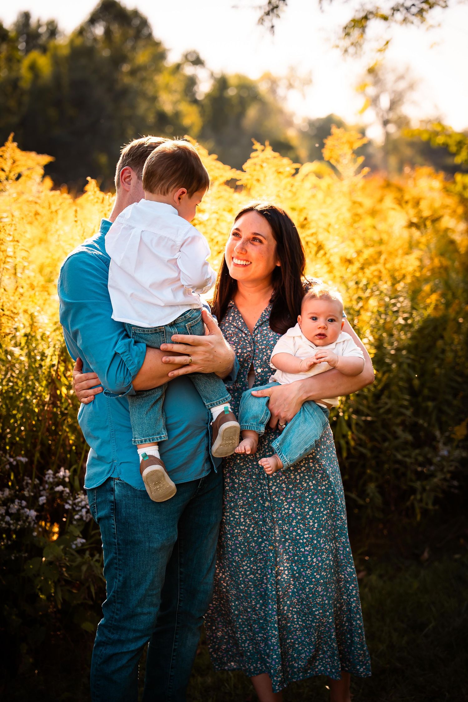 Family in blue and floral outfits playing with children during golden hour photoshoot.