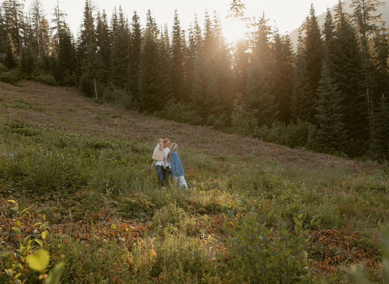 Three candid outdoor photos of a couple walking on rocky terrain with evergreen trees and golden sunlight in the background.