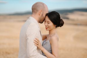 Couple embracing in a romantic moment against a desert landscape during golden hour.