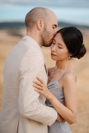 Intimate couple embracing in a series of romantic poses wearing light colored formal attire.
