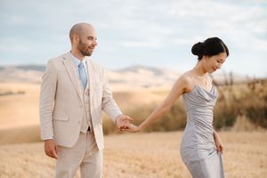 A couple in light-colored wedding attire poses together against a scenic desert landscape during a photoshoot.