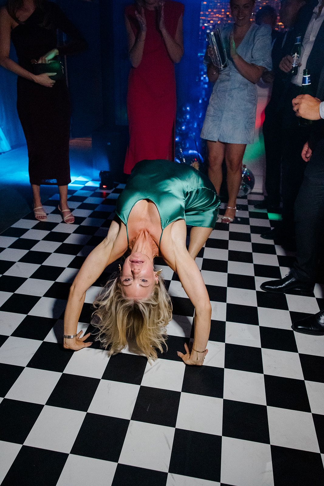 Dancer performs a backbend on black and white checkered dance floor with blue lighting in the background.
