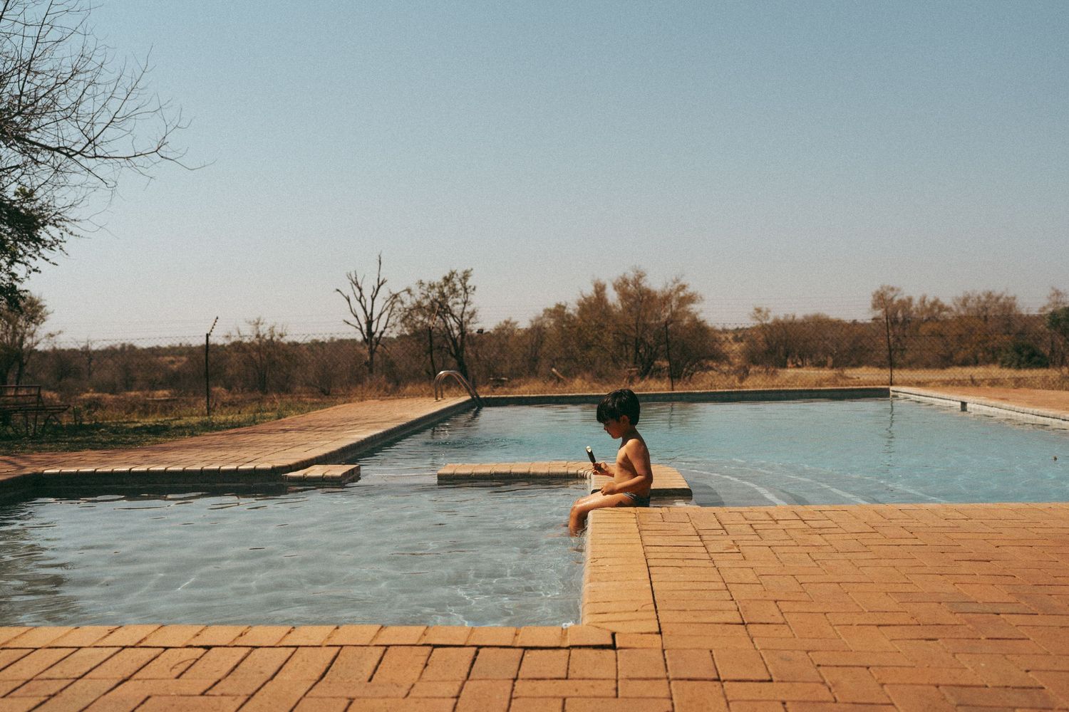 Swimming pool with wooden deck against desert landscape.