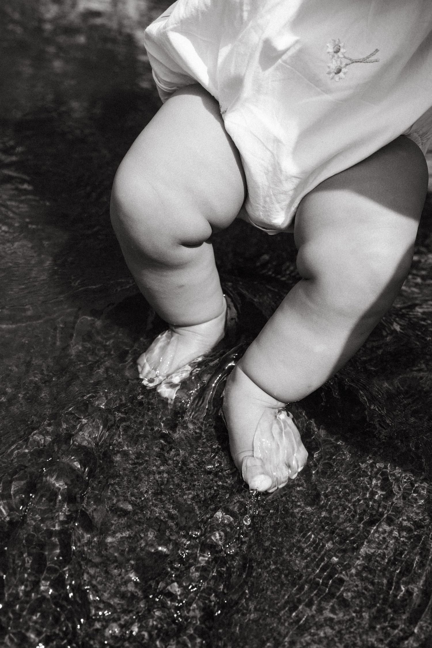 Close-up shots of small feet touching wet rocks near water.