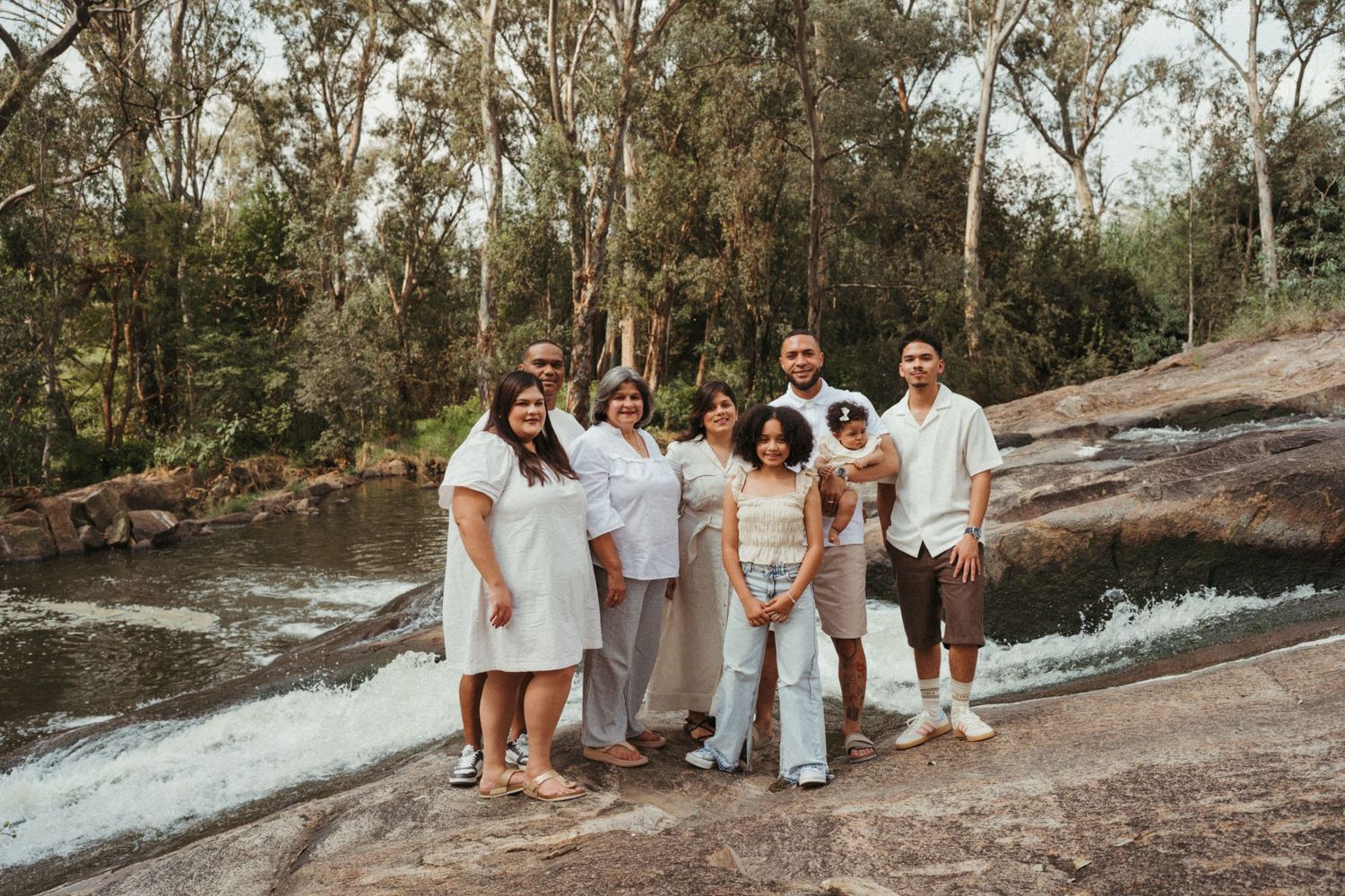 Group photo session on rocky outcrop surrounded by trees and flowing water.