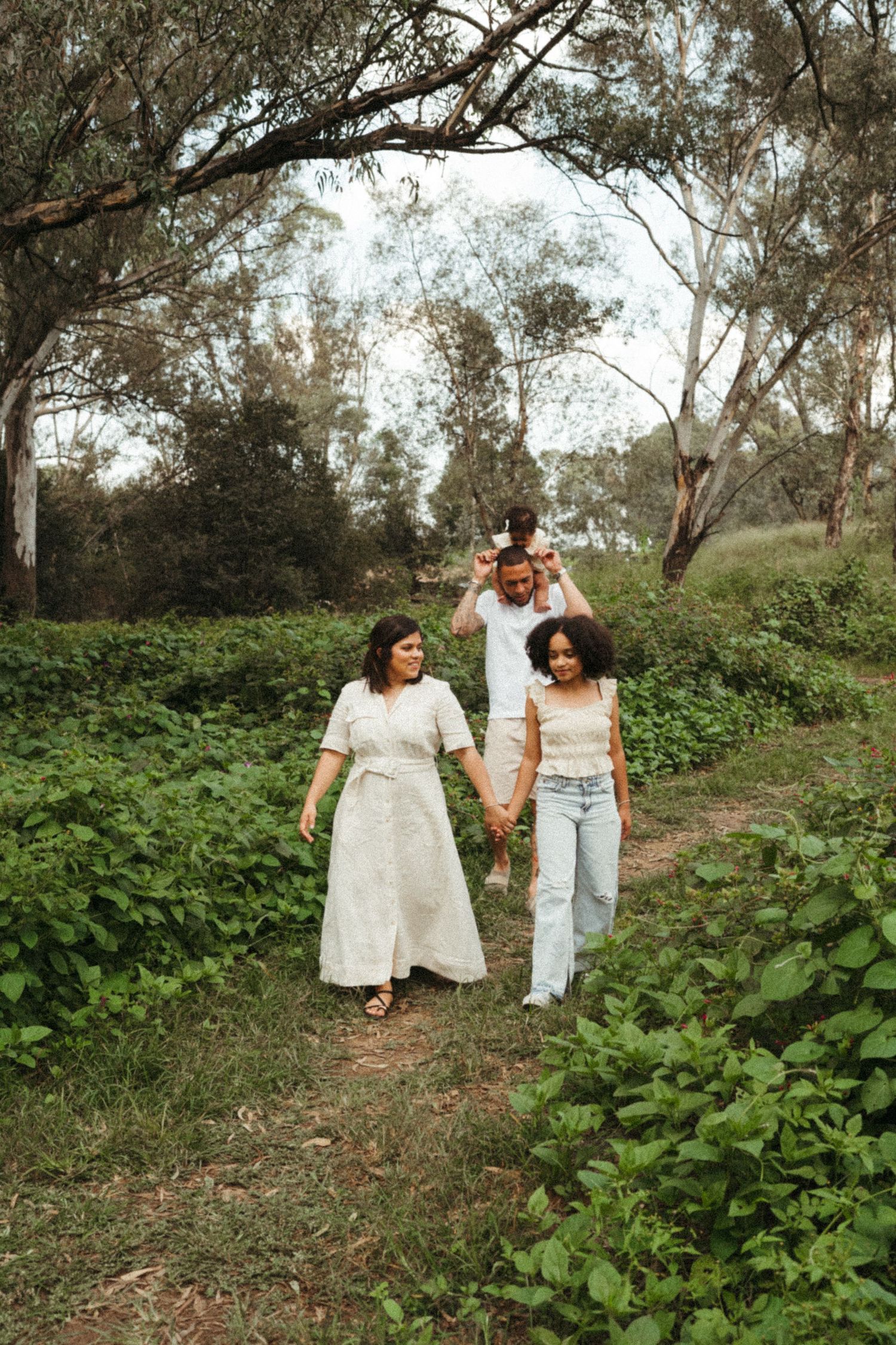 Family walking together through a lush green outdoor path.