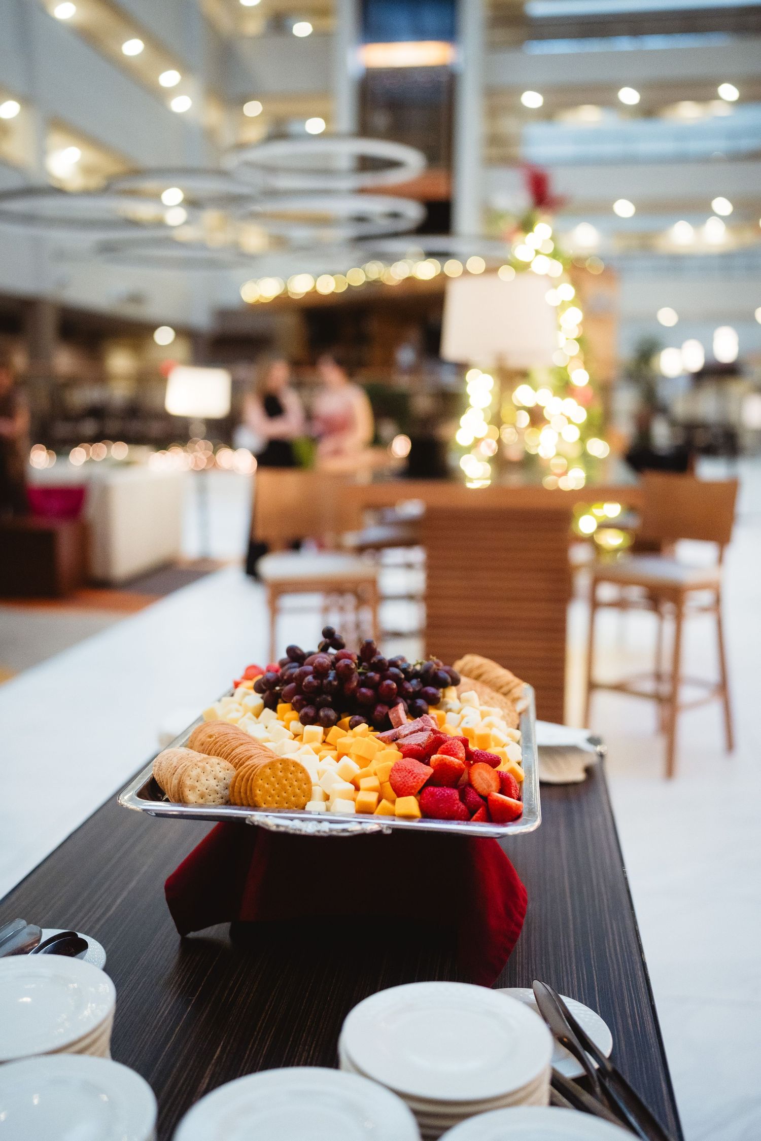Elegant dessert plates with fresh berries and pastries arranged on dark tables in an upscale dining room.
