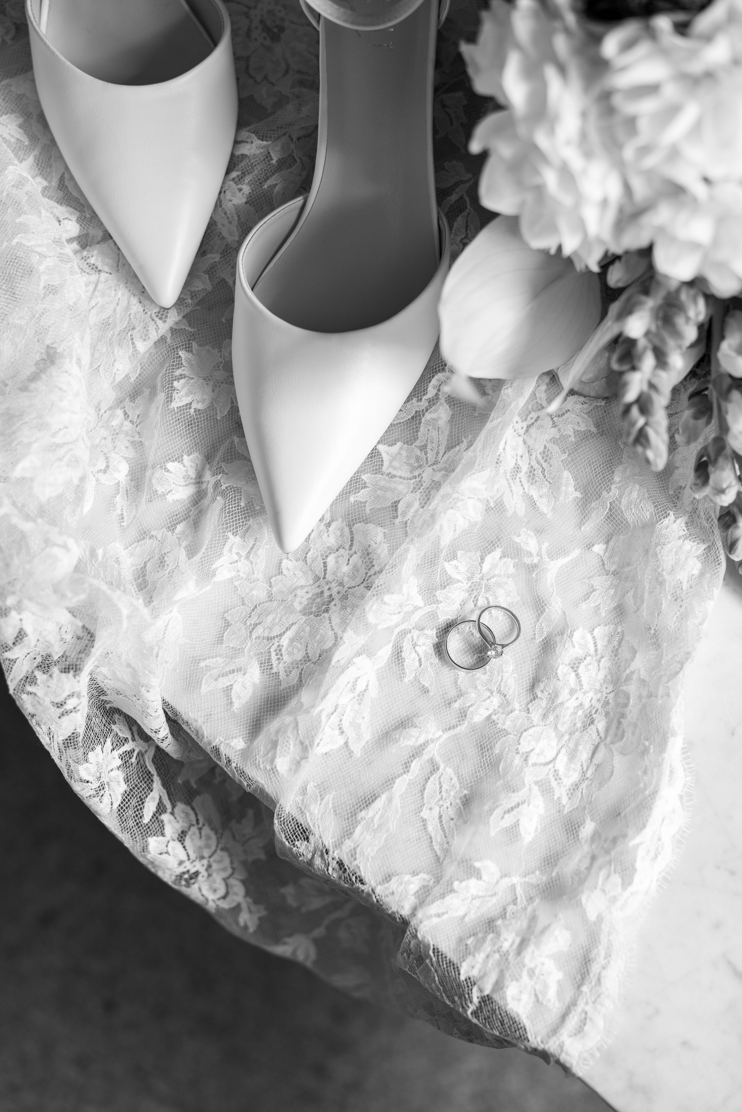 Close-up detail shot of white lace wedding dress fabric with wedding rings.