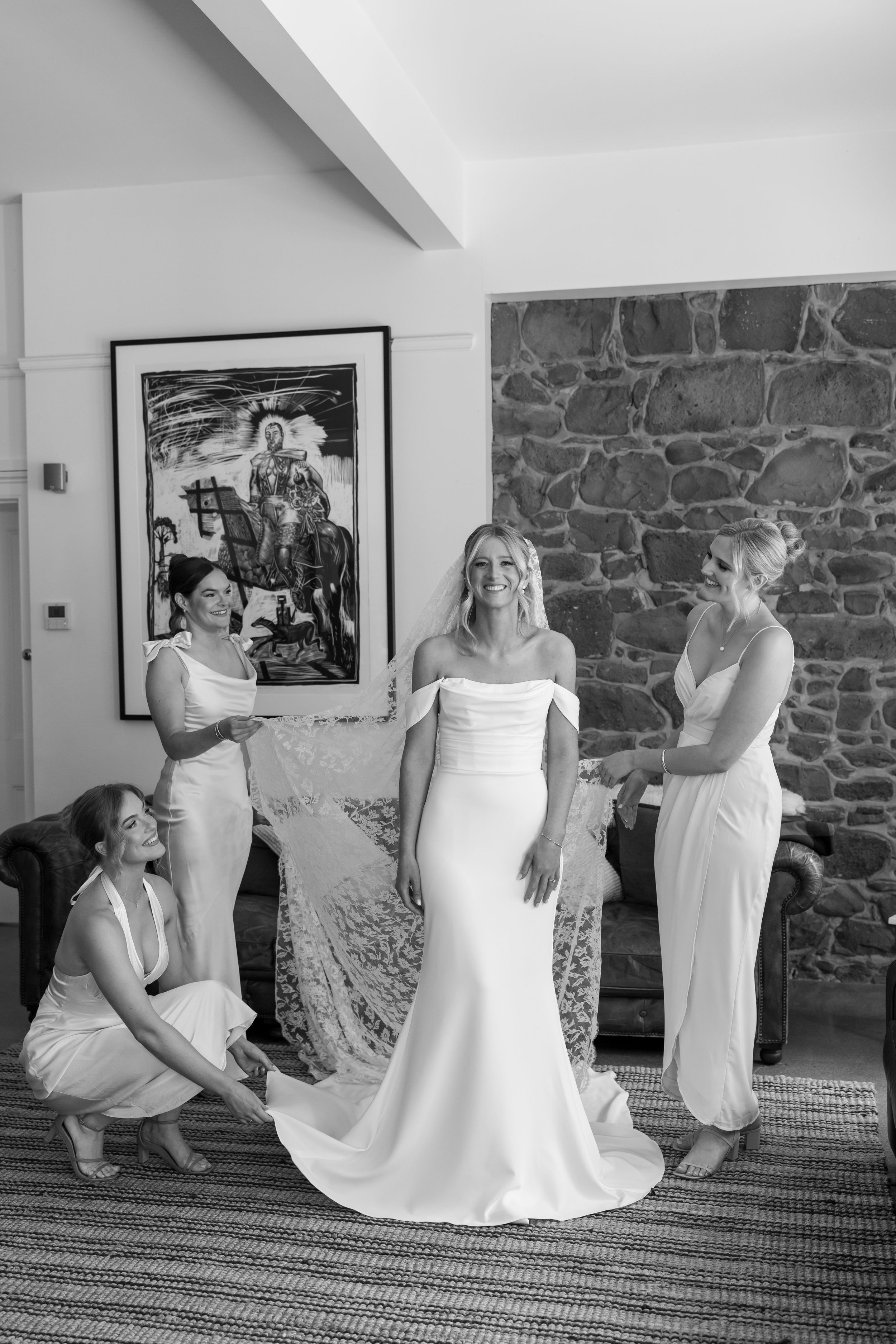 Black and white sequence showing preparations in a room with stone walls and framed artwork.