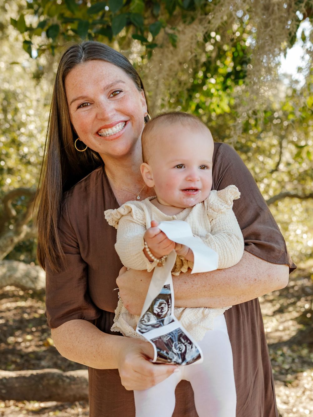 Sweet candid moments captured of a baby in white clothing being held against brown clothing.