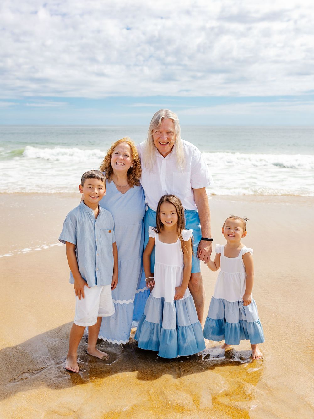 Happy group wearing matching blue and white outfits poses together on a sunny beach.