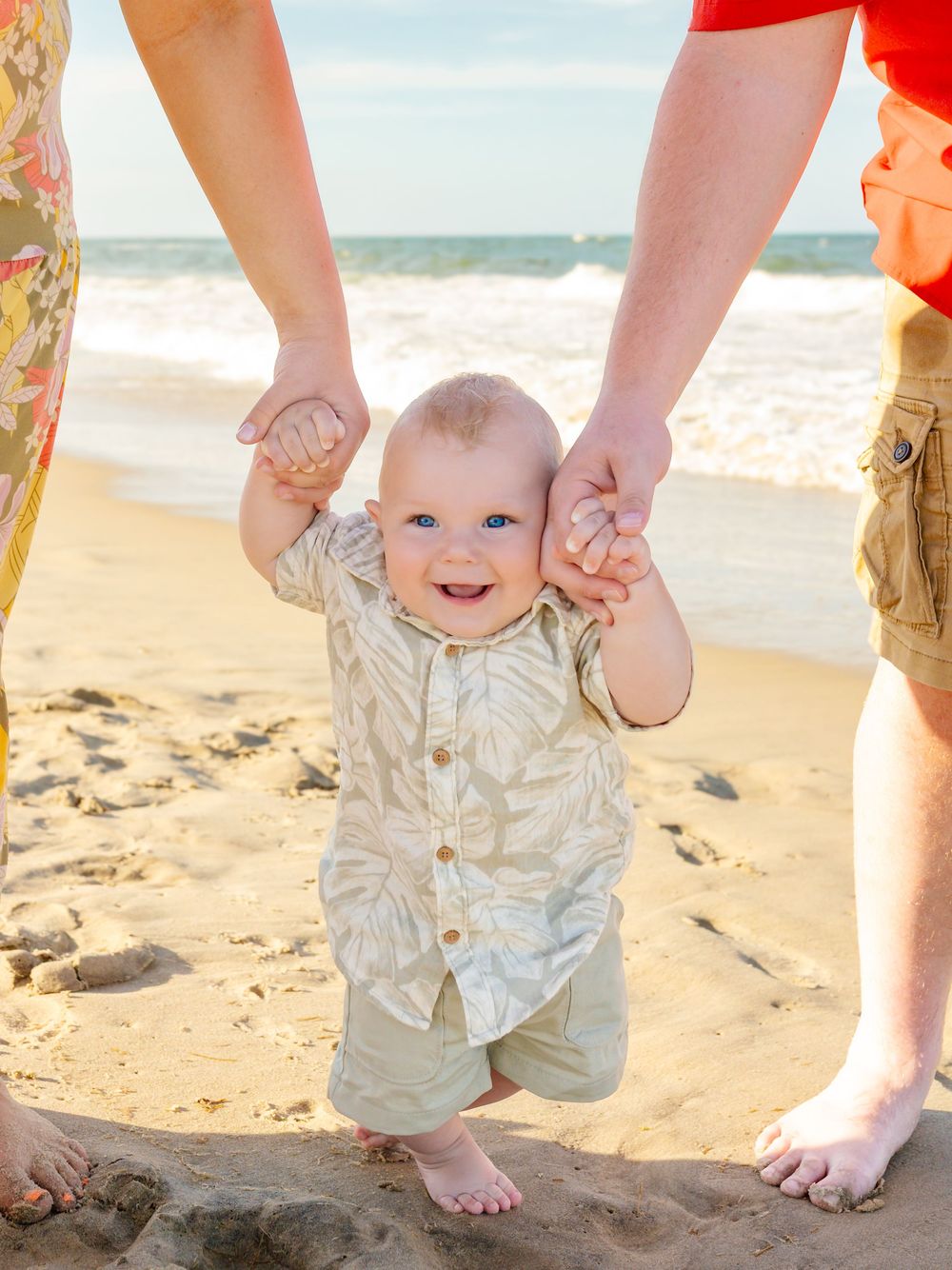 Joyful beach photo series showing baby being lifted in the air over sand.