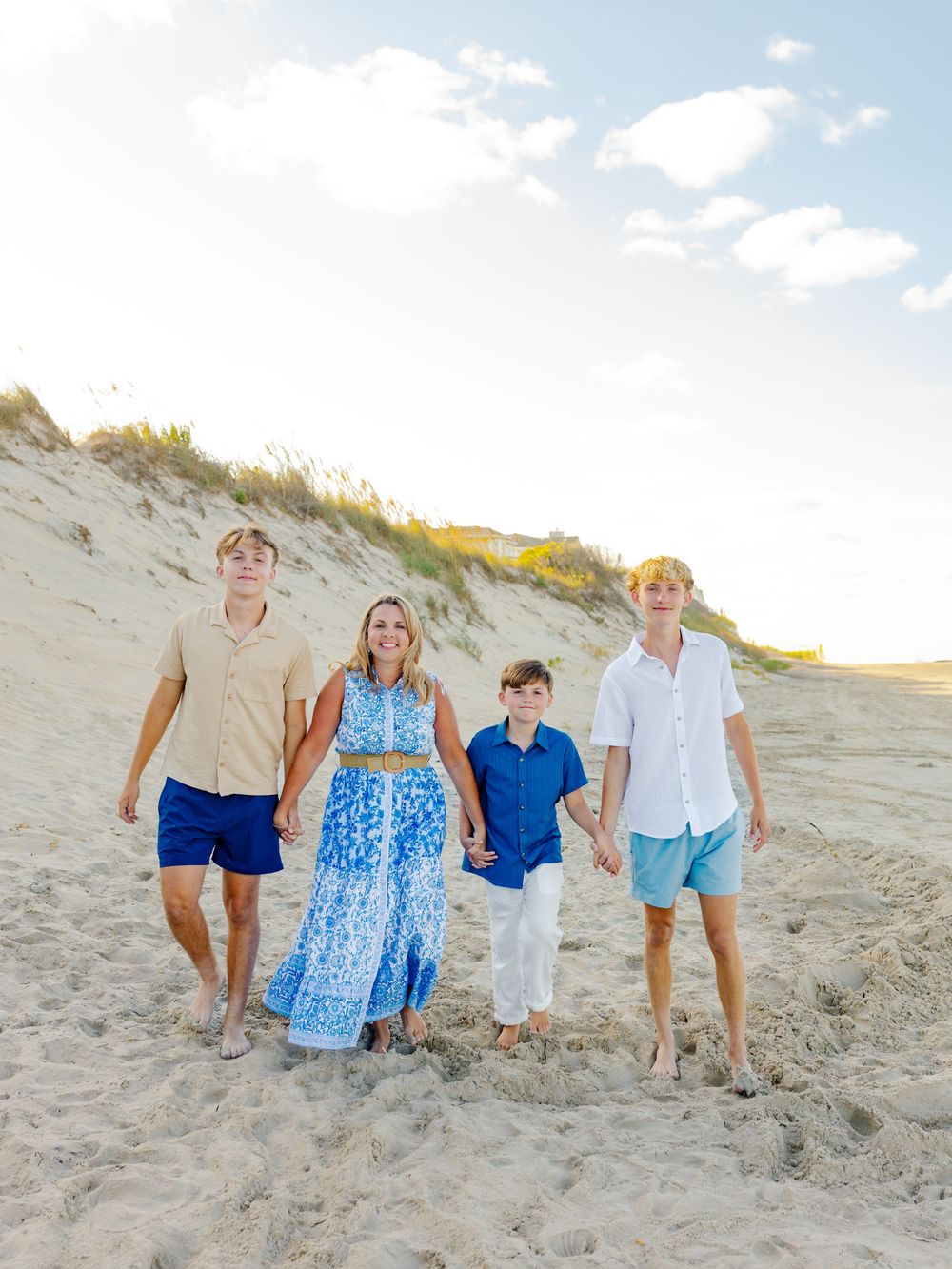 Group walking together down a sandy beach hill in coordinated blue and white beachwear.