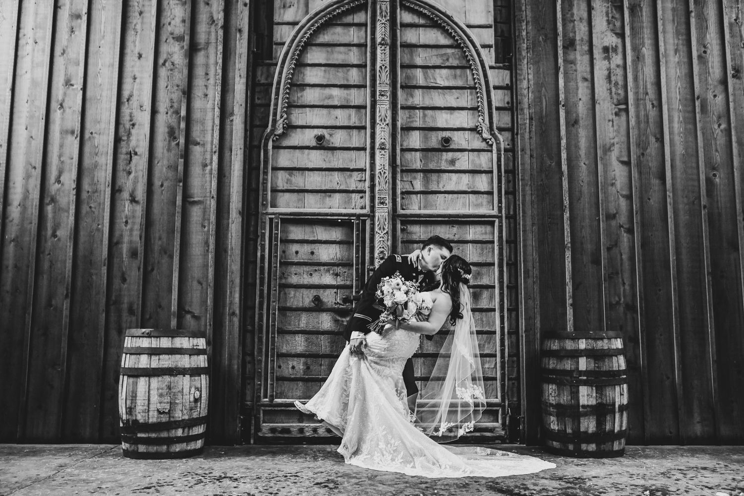 Bride and groom standing in front of rustic Lucky Spur Ranch doors for an elegant editorial portrait.