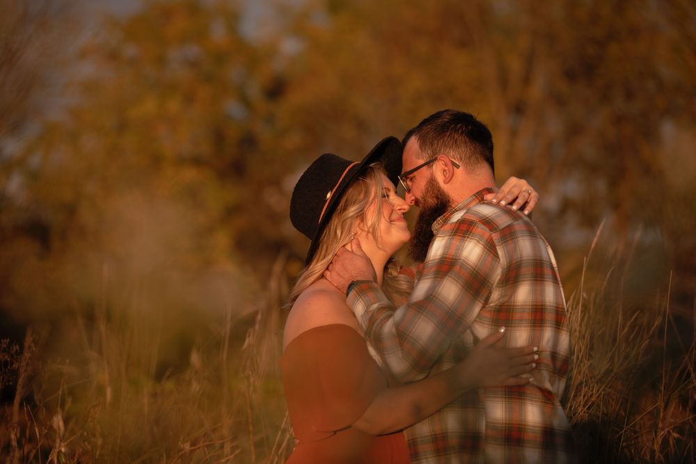 A couple embraces tenderly in a golden field at sunset creating a romantic silhouette against the warm light.