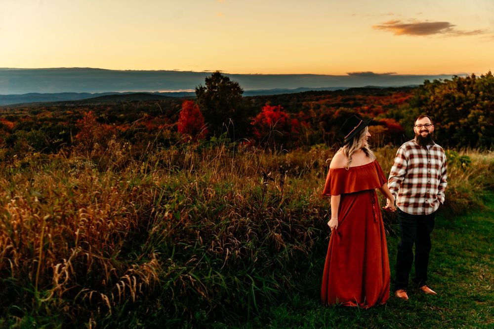 A couple enjoys a romantic sunset moment in a field of autumn wildflowers and tall grass.