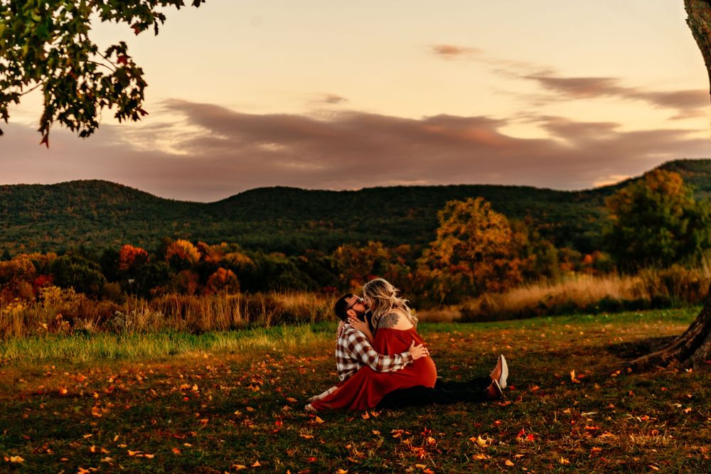 A scenic autumn hillside with golden foliage and mountains in the background during sunset.