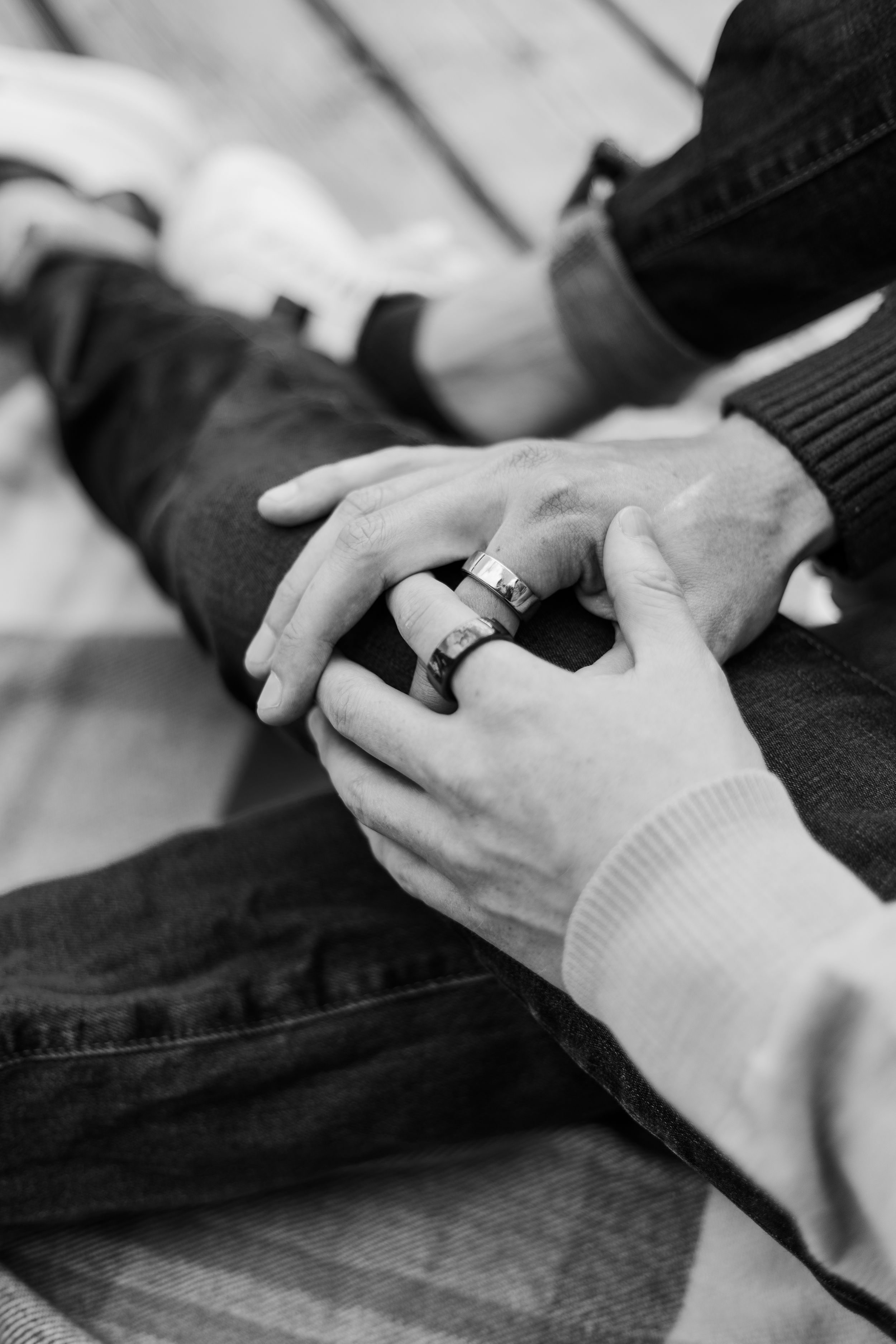 Close-up black and white photo of hands repairing denim jeans with needle and thread.